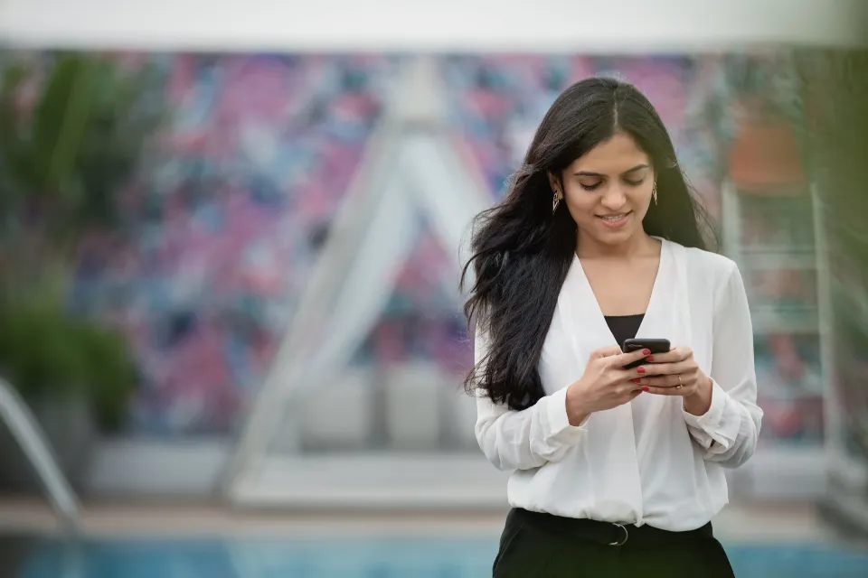 Mulher a consultar o telemóvel antes de comprar.